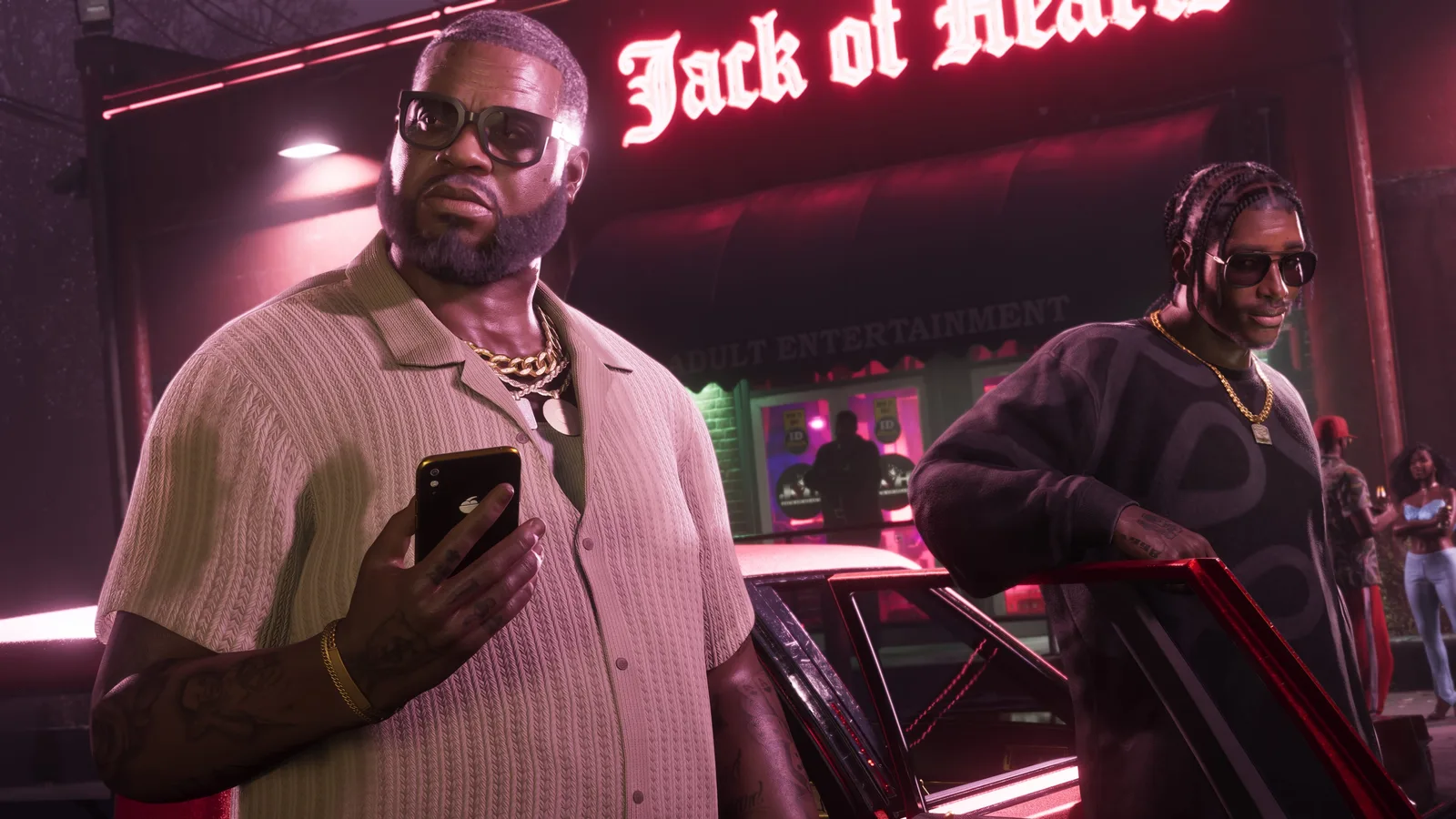 Boobie and Dre'Quan exiting a car; Boobie holds his phone while Dre'Quan leans on the open door.