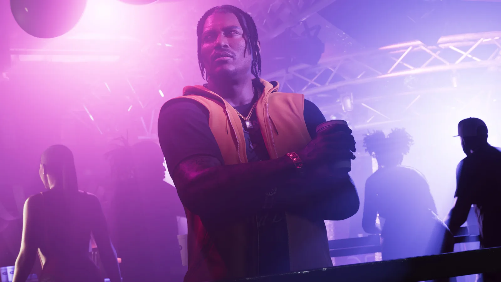 Dre'Quan in a club, arms crossed with a drink in hand, looking off to the side.